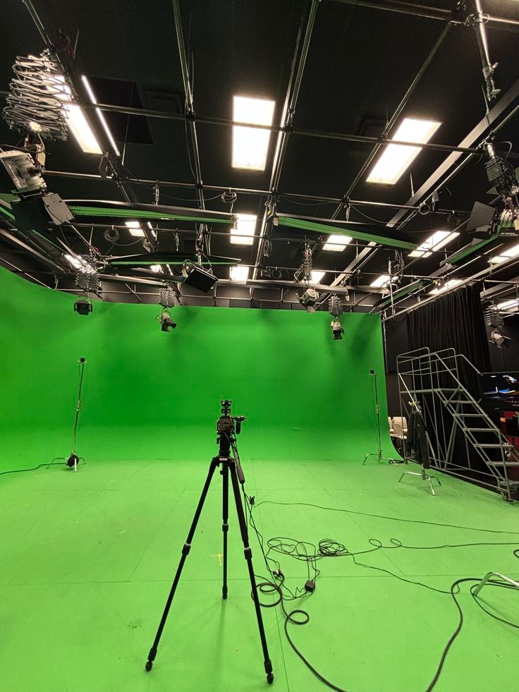 Empty chroma key green screen studio with ceiling lights and camera on tripod