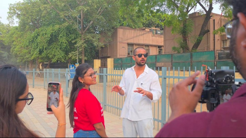 Founder directing a movie shoot on location next to a metal fence