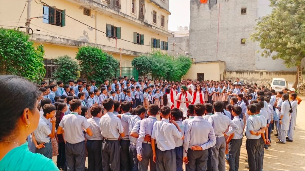 Street play performance in front of school children in uniform watching the actors in the yard